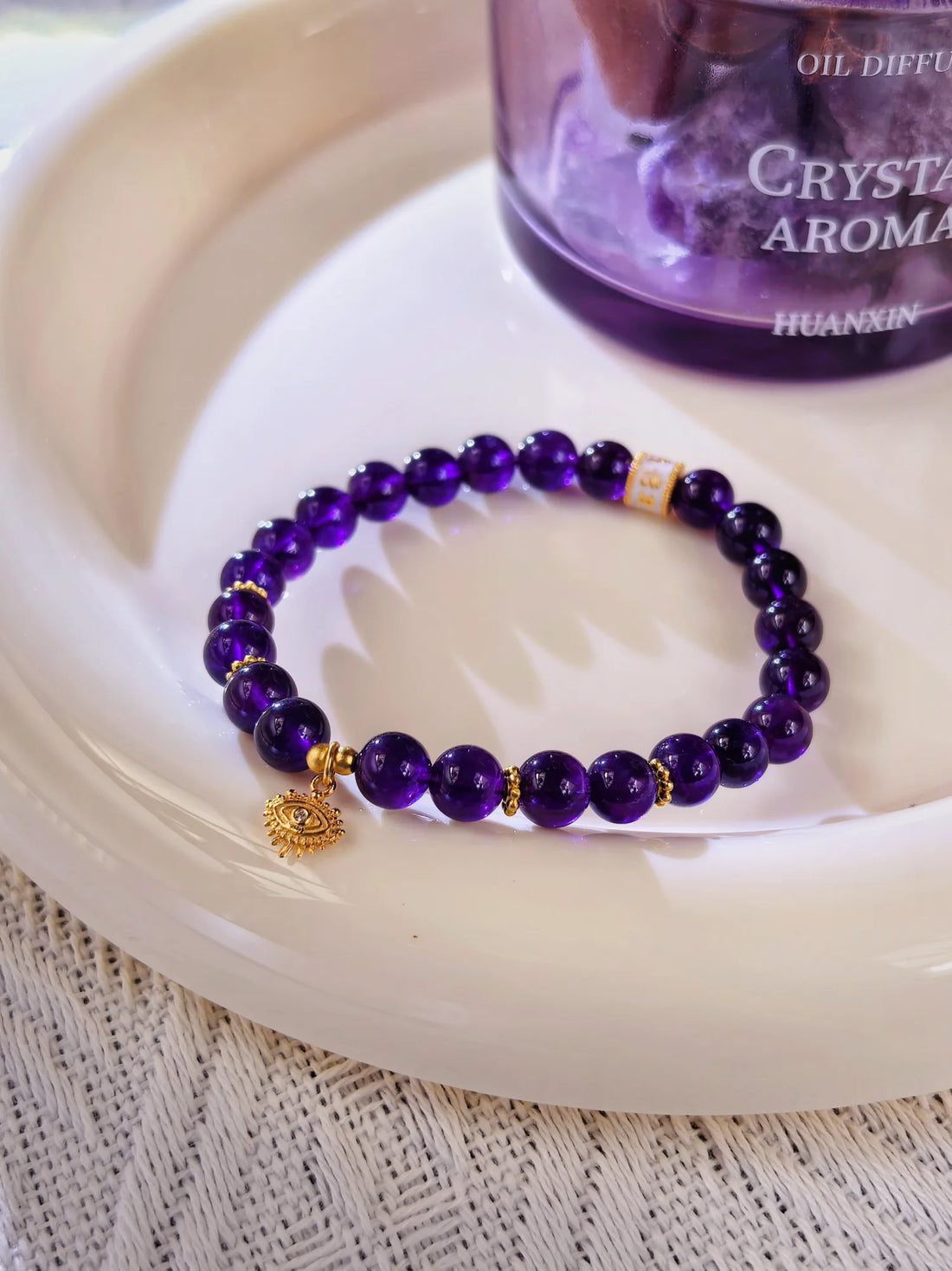 Amethyst beaded bracelet with an evil eye charm lying on a plate.