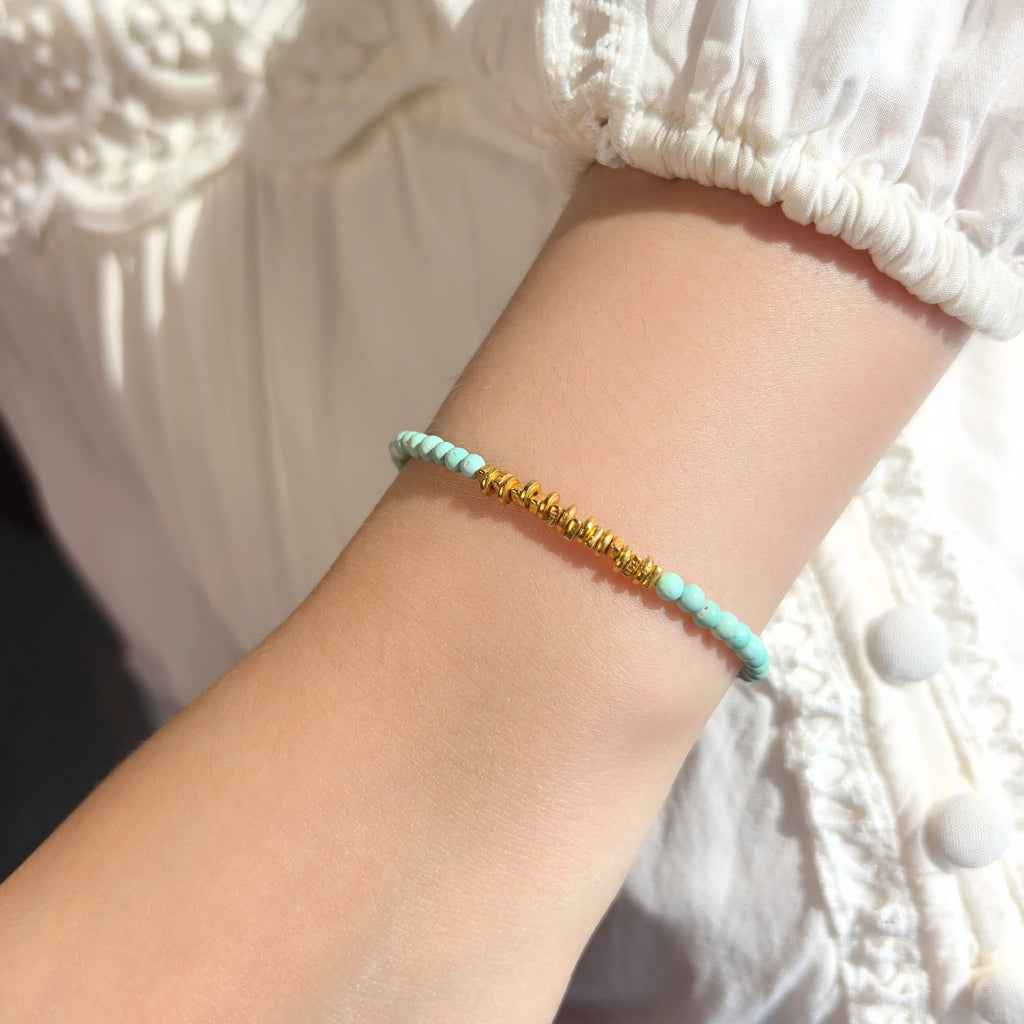 Woman wearing Calm Tide turquoise chip gold bracelet on wrist, minimalist stacking throat chakra crystal jewelry