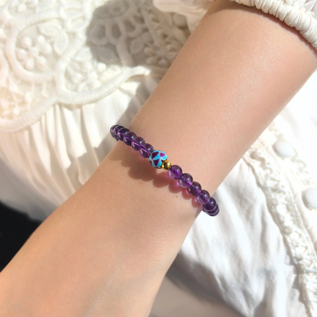 Female model wearing delicate Amethyst Lotus Bloom Bracelet on wrist, your third eye and crown chakras, clearing mental fog and boosting inner intuition. 