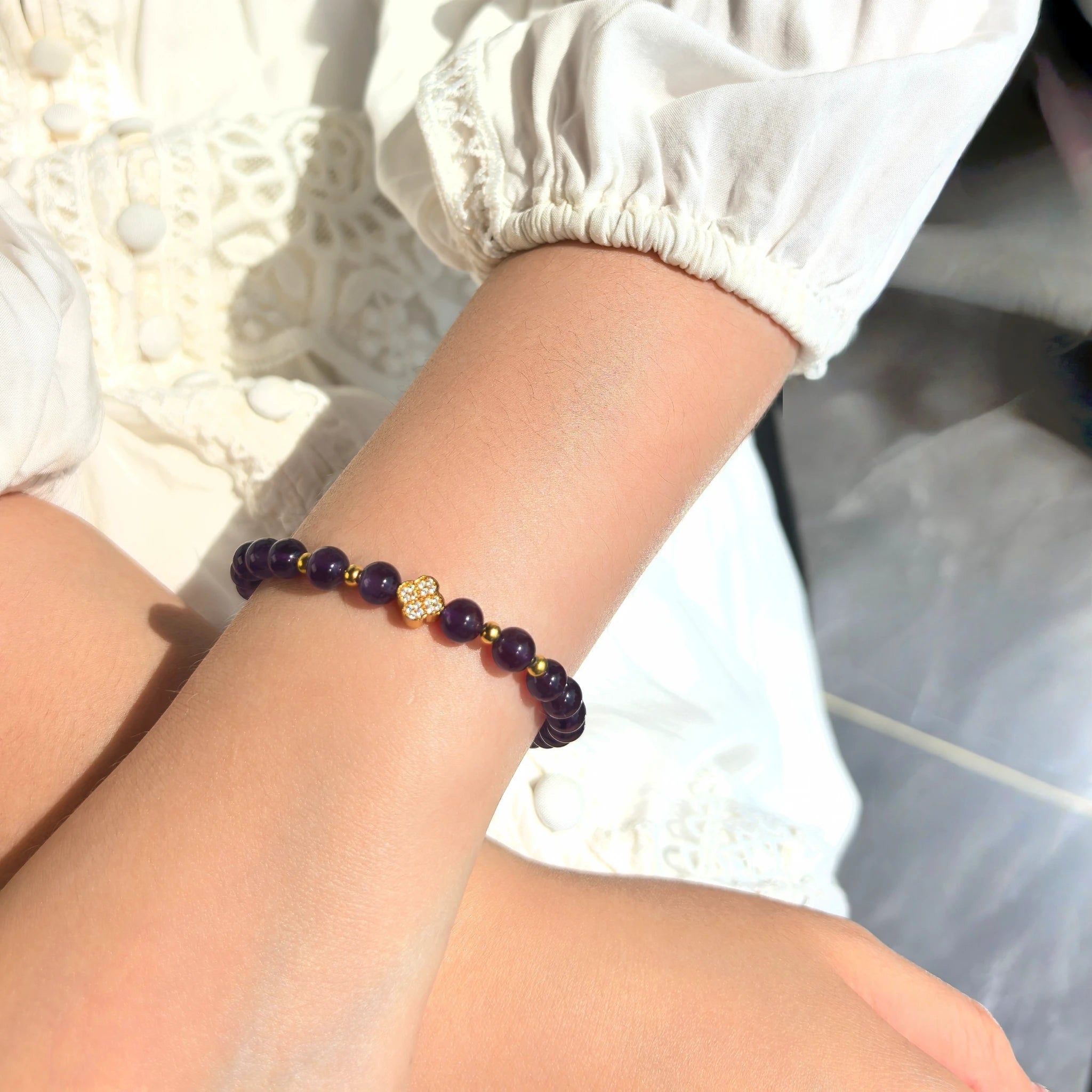 Female model wearing elegant Amethyst Lucky Clover Mantra Bracelet on wrist, stackable purple spiritual crystal for daily wear.