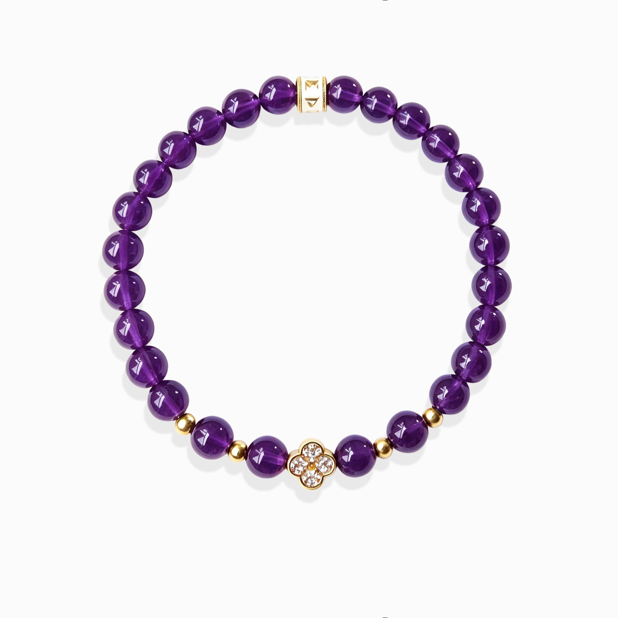 Close-up detail of sparkling pave crystal lucky clover pendant and golden mantra spacer bead on deep purple amethyst mantra bracelet