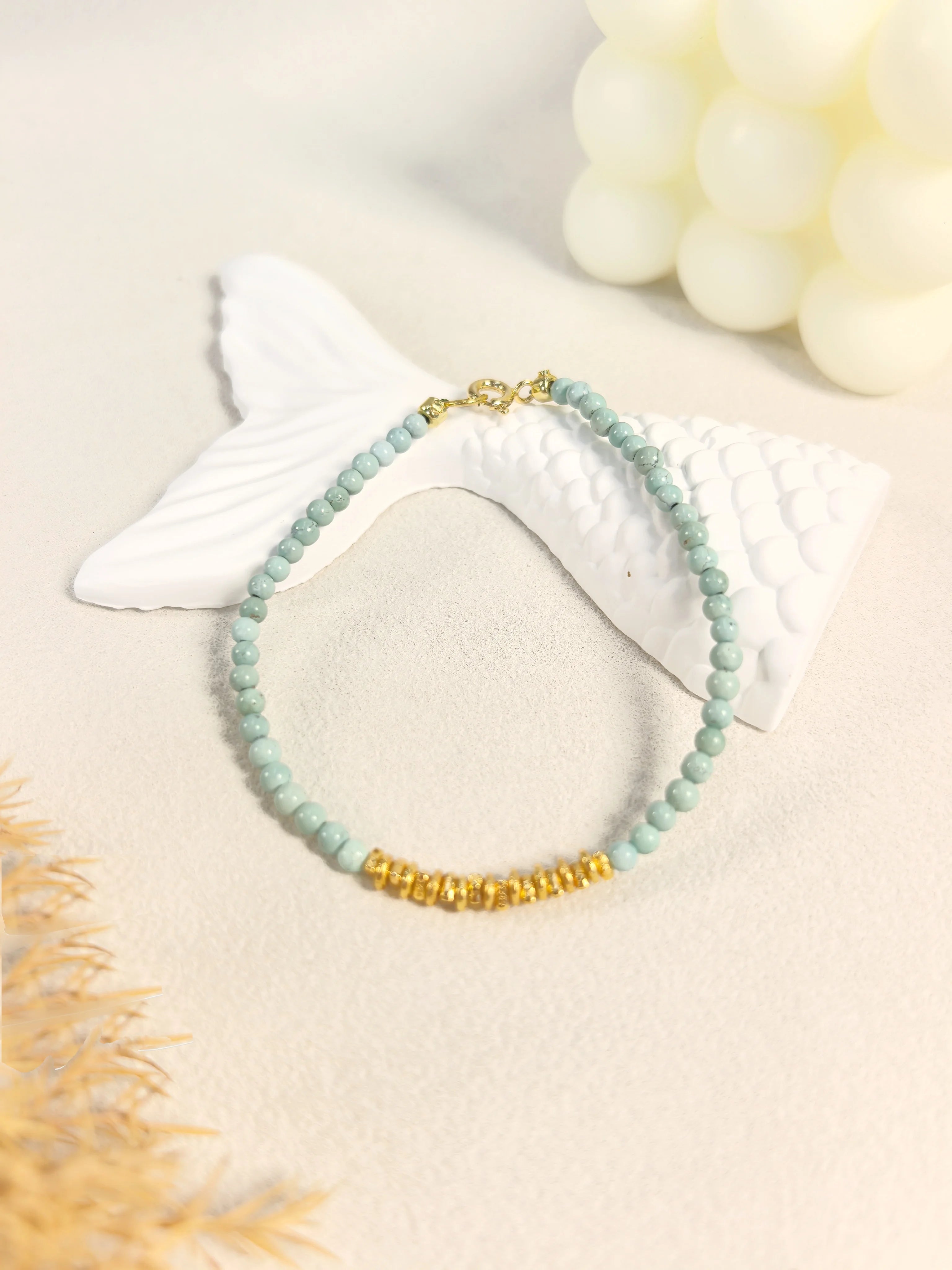 Ins coastal aesthetic flat lay of Calm Tide turquoise chip bracelet with white mermaid tail decor, serene ocean crystal jewelry