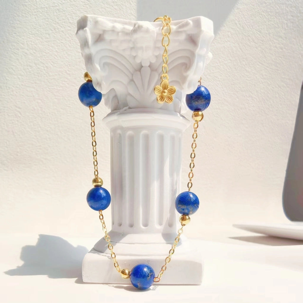 Close-up of delicate gold four leaf clover charm and adjustable extension chain on Milky Way Stroll Lapis Lazuli Bracelet，throat chakra crystal jewelry。