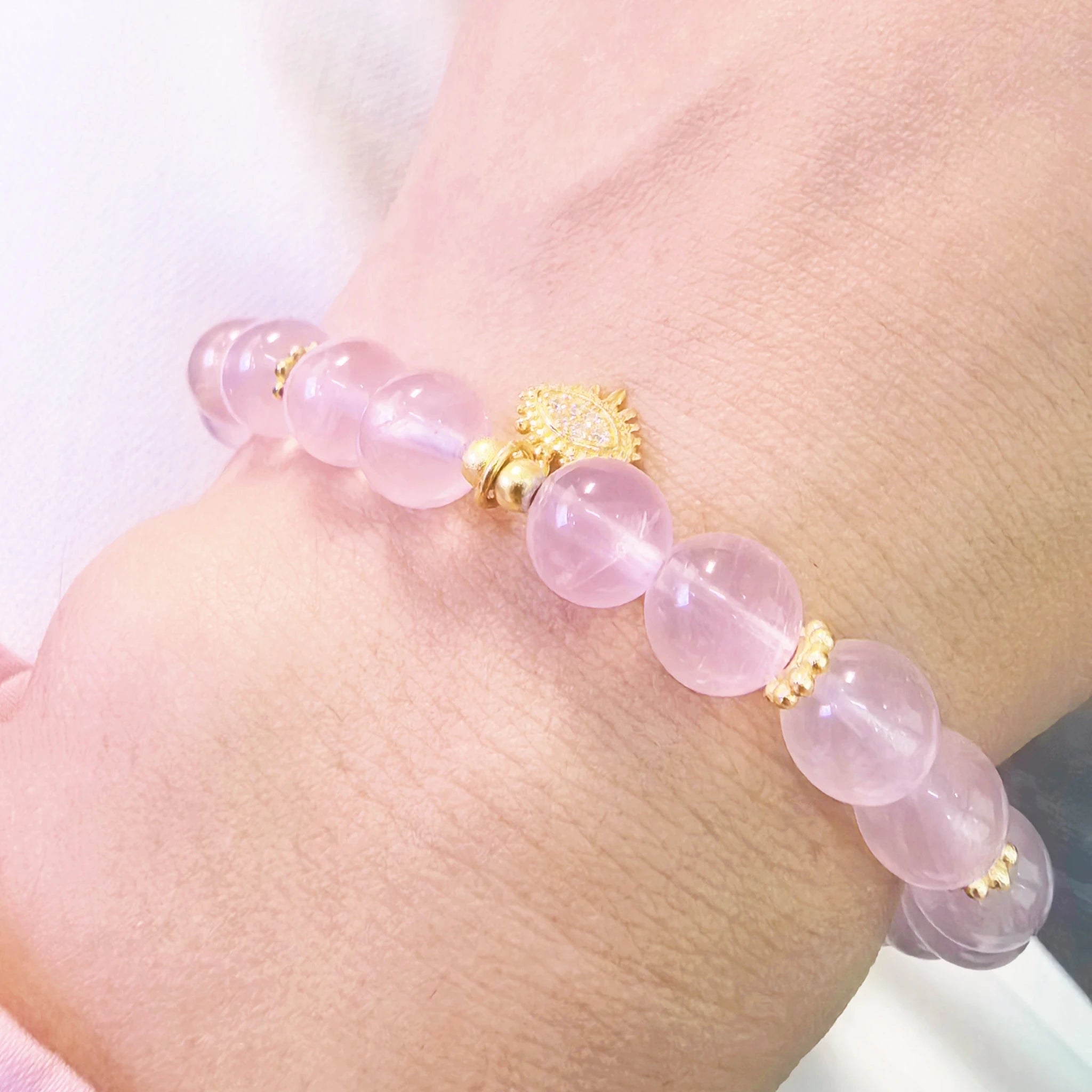 Close-up shot of evil eye protection pendant on translucent pink aura crystal bracelet