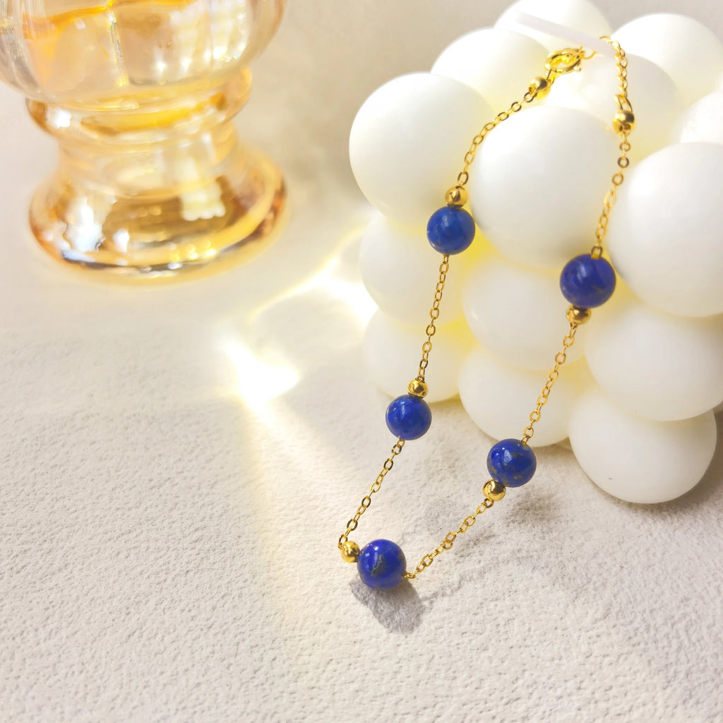 Soft ins style still life shot of Milky Way Stroll Lapis Lazuli Bracelet, galaxy-inspired deep blue lapis spiritual jewelry with gold clover charm