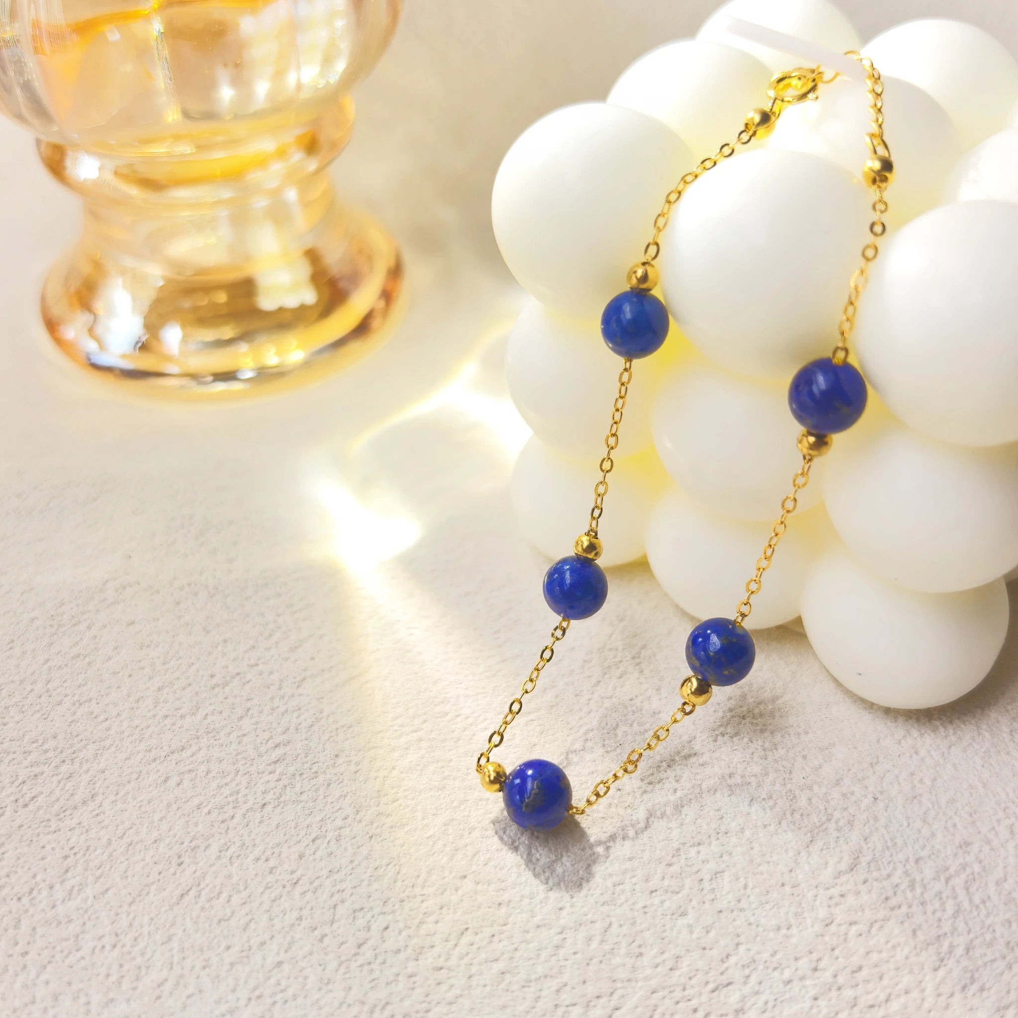 Soft ins style still life shot of Milky Way Stroll Lapis Lazuli Bracelet, galaxy-inspired deep blue lapis spiritual jewelry with gold clover charm