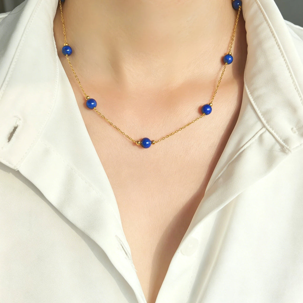 Woman wearing Milky Way Stroll lapis lazuli gold necklace with white shirt, minimalist blue gem layering choker on neck