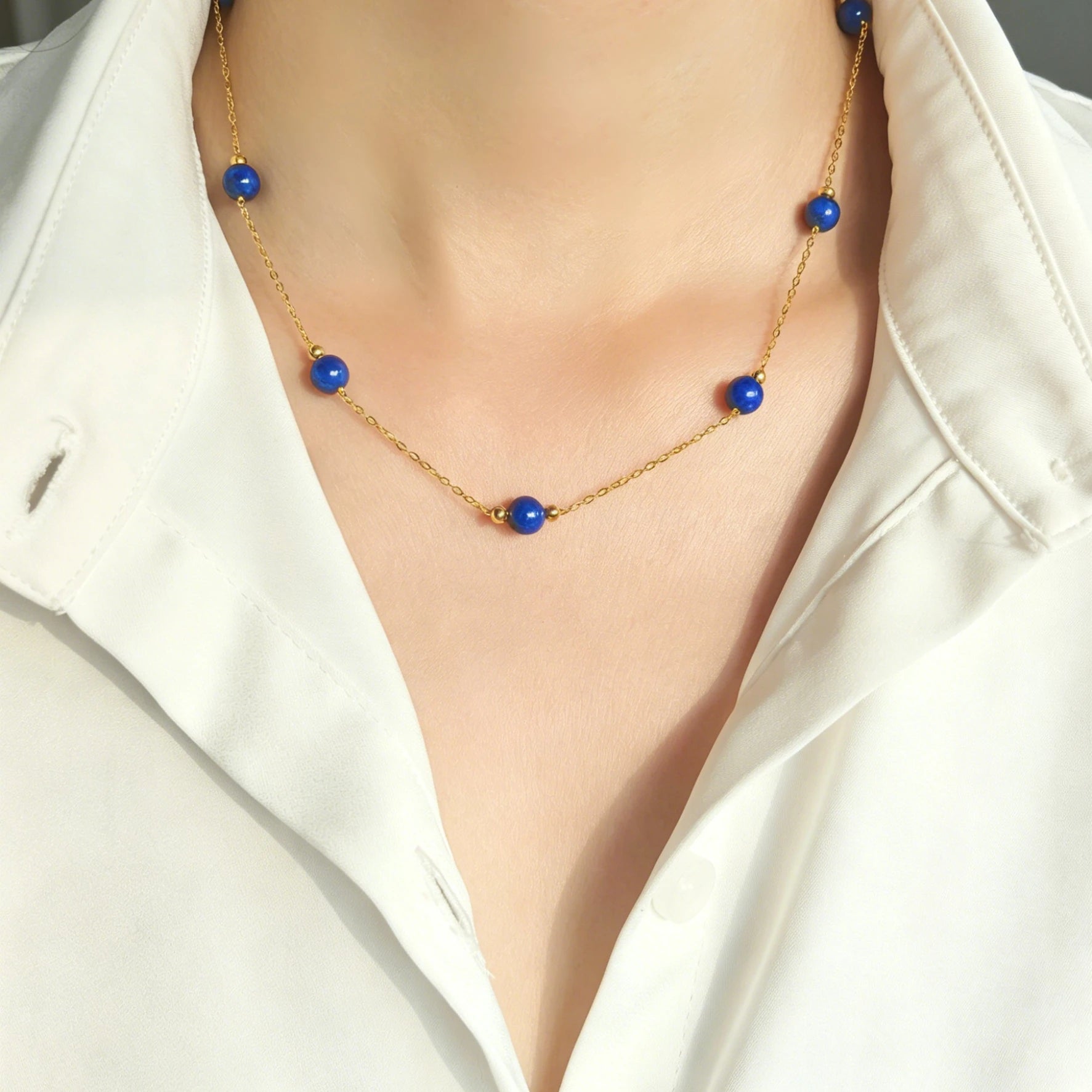 Woman wearing Milky Way Stroll lapis lazuli gold necklace with white shirt, minimalist blue gem layering choker on neck