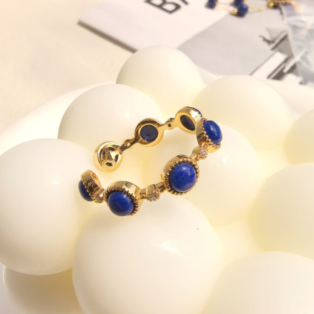 Close up detail of polished natural lapis lazuli cabochon and textured gold frame on milky way stroll adjustable open ring