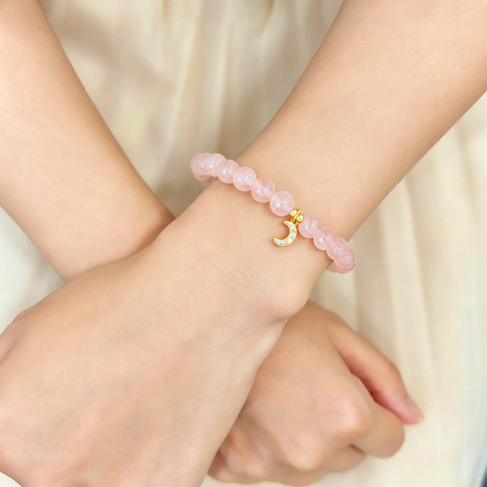 Rose quartz crescent moon charm bracelet worn on wrist