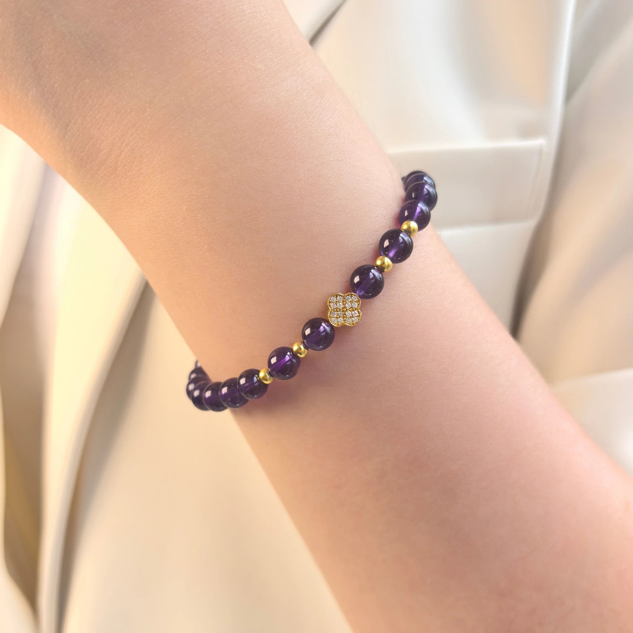 Female model wearing elegant Amethyst Lucky Clover Mantra Bracelet on wrist, minimalist purple spiritual crystal everyday accessory