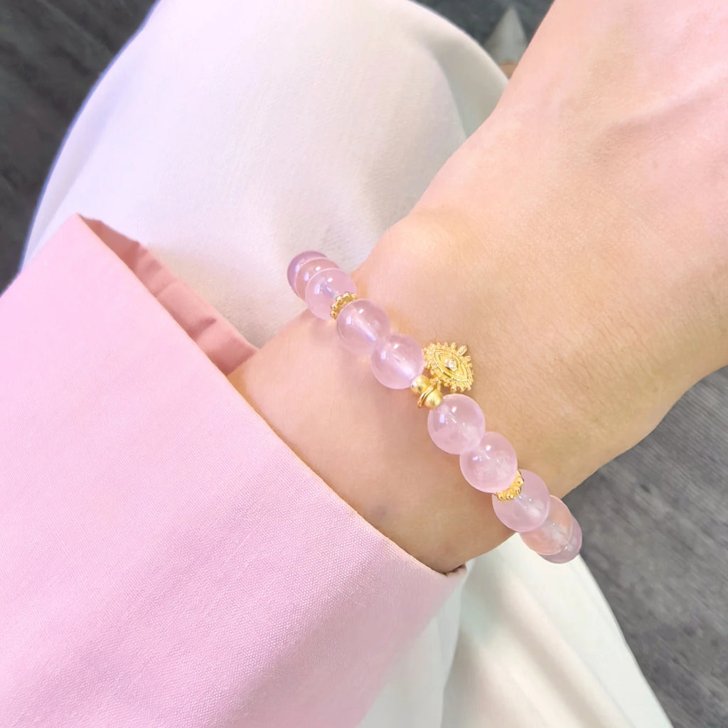 Female model wearing soft luminous pink aura evil eye protection bracelet on wrist, minimalist boho spiritual everyday crystal accessory